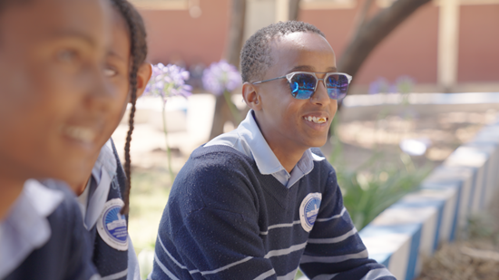 Teenager sits on wall and smiles into the distance